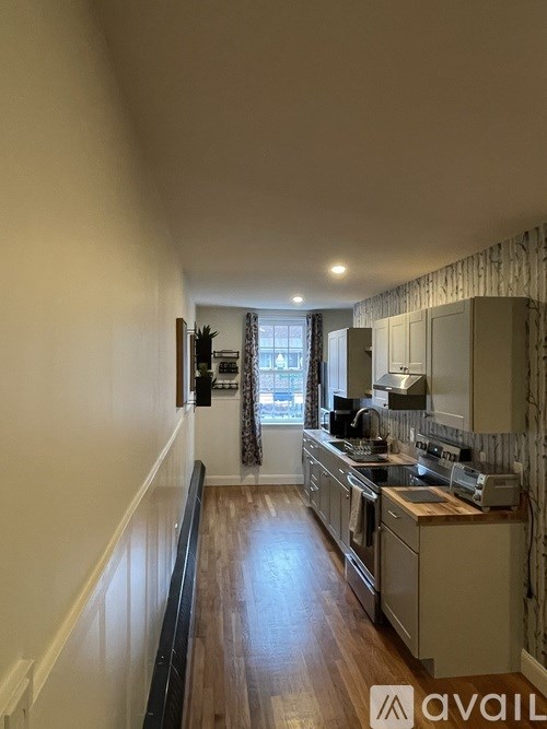 A kitchen with wooden floors and white walls.