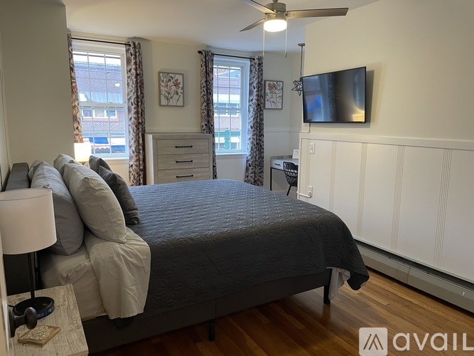 A bedroom with a bed, a ceiling fan, and a television.