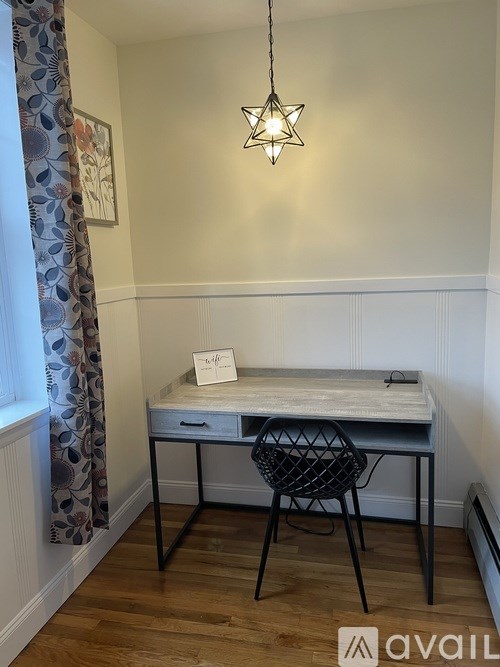 A desk with a chair and a hanging light fixture in a room.