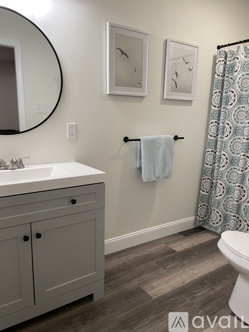 A bathroom with a white sink and a grey cabinet.