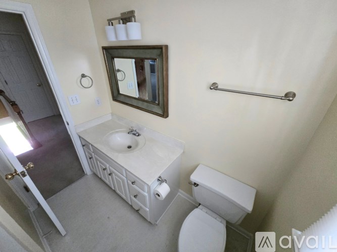 A bathroom with a toilet, sink, mirror, and towel rack.