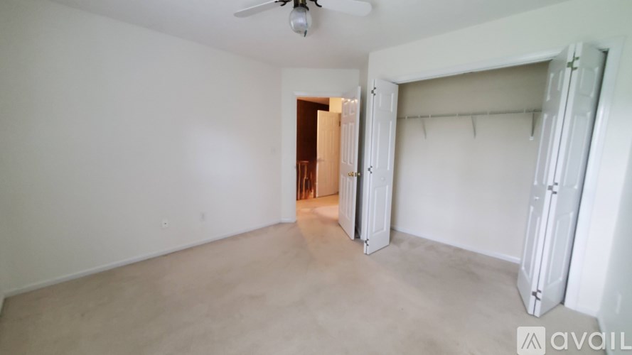 A room with a ceiling fan and a doorway leading to another room.