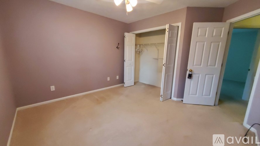 A room with a white door and a brown floor.