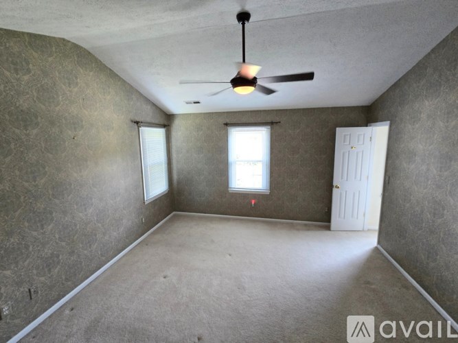A room with a ceiling fan and two windows.
