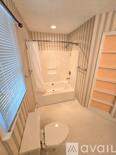 A bathroom with a toilet, a shower with a glass door, and striped wallpaper.
