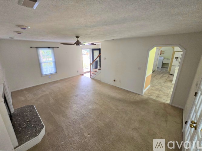 A spacious room with a fan, a window, and a staircase.