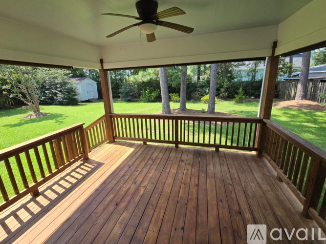 A wooden deck with a ceiling fan and a view of a yard.
