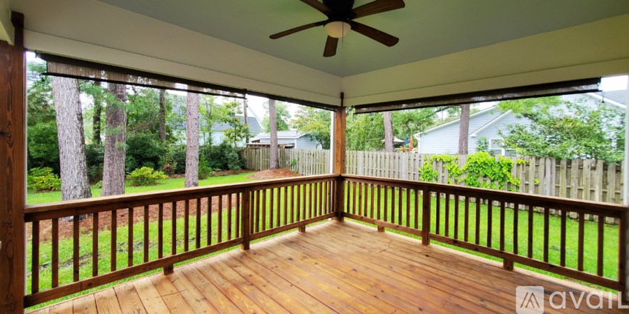 A wooden deck with a ceiling fan and a view of a backyard.