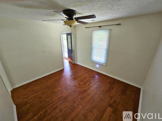 A room with a ceiling fan and wooden flooring.