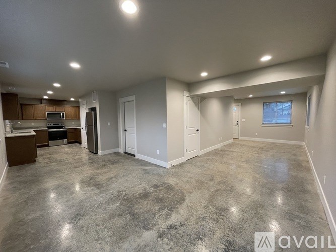 A spacious living room with a kitchen area in the background.