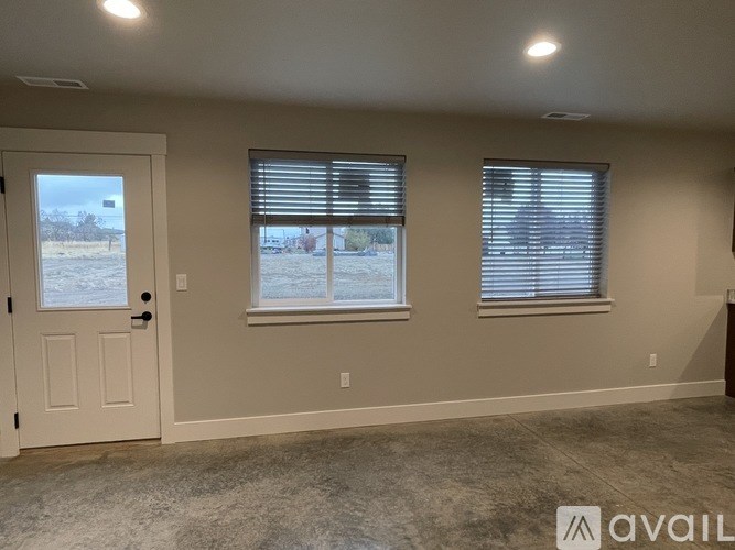 A room with a door, two windows, and a carpeted floor.