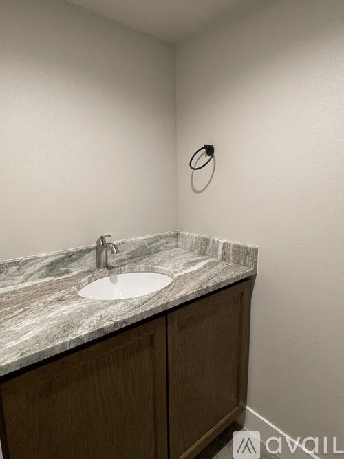 A bathroom with a marble countertop and a round mirror.