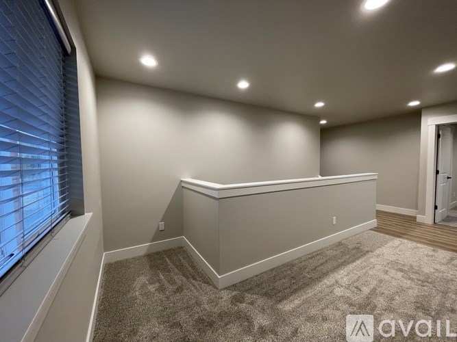 A room with a carpeted floor and a window with blinds.