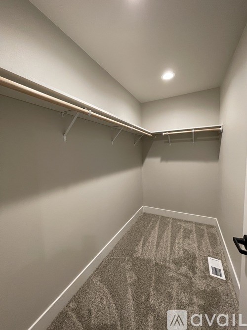 A room with a carpeted floor and a wall-mounted coat rack.