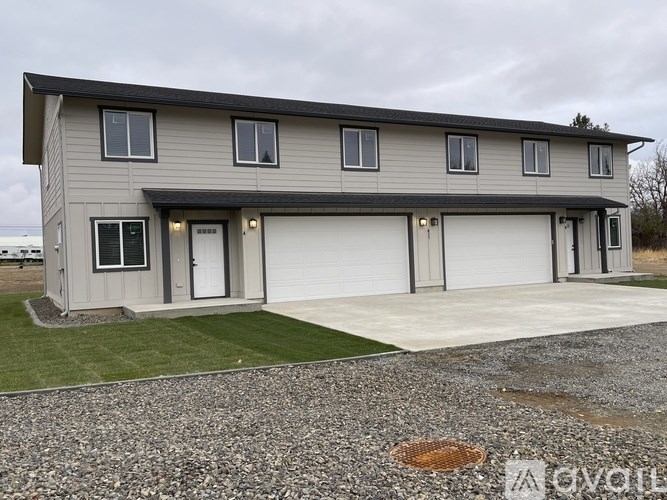 A two-story house with a garage and a gravel driveway.