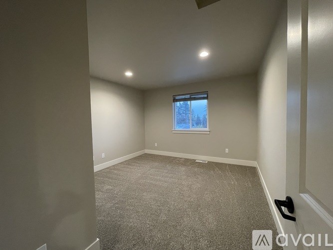 A room with a carpeted floor and a window showing a snowy landscape outside.