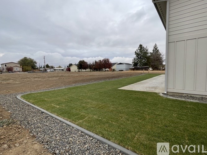 A grassy area with a gravel path and a building on the right side.