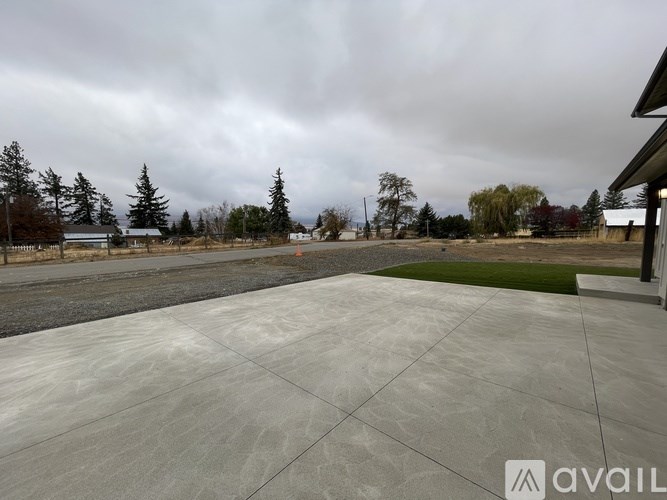 A concrete patio with a dark sky overhead and trees in the distance.