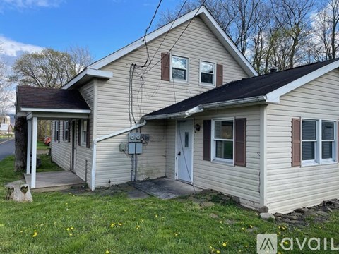 A house with a beige siding and a white door is for sale.