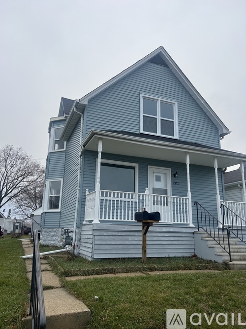 A blue house with a white porch and a mailbox on the front.