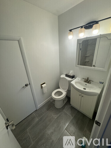 A bathroom with a toilet, sink, and mirror.