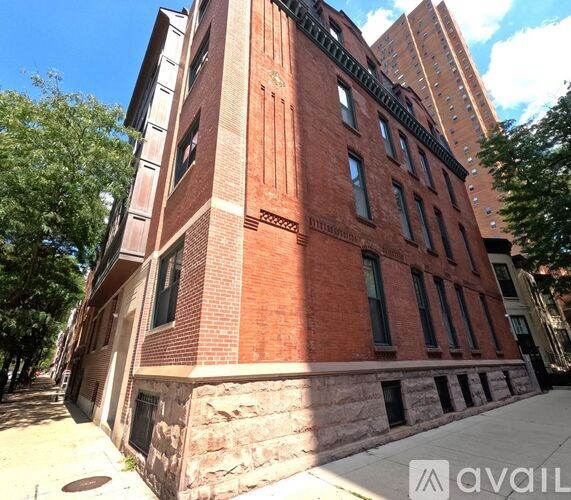 A red brick building with a stone foundation and a tree in front.