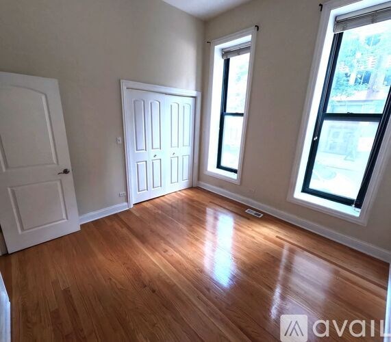 A room with wooden floors and two windows.