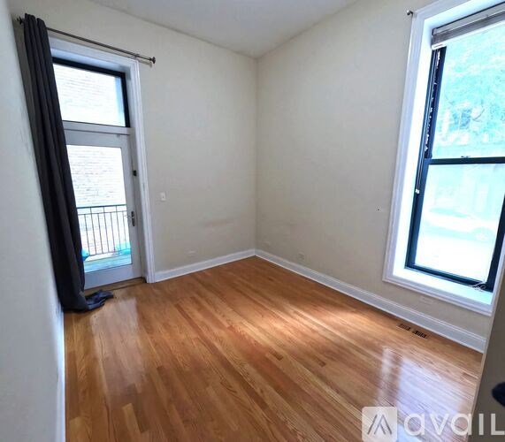 A room with wooden flooring and a window with a view of a balcony.