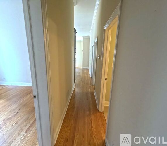 A long hallway with wood floors and white walls.