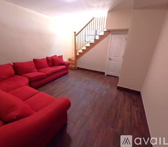 A living room with red couches and a wooden staircase.