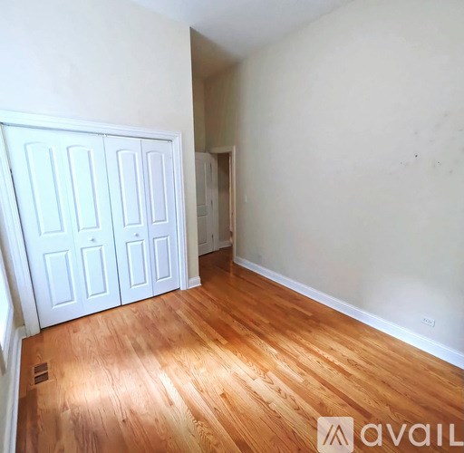 A room with wooden floors and white walls, with a white door on the left.