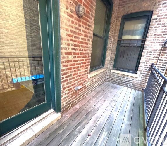 A wooden deck with a green door and a window.