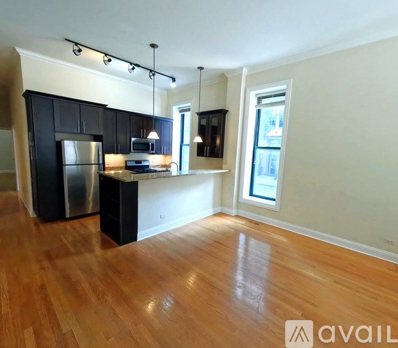 A kitchen with black cabinets and a wooden floor.