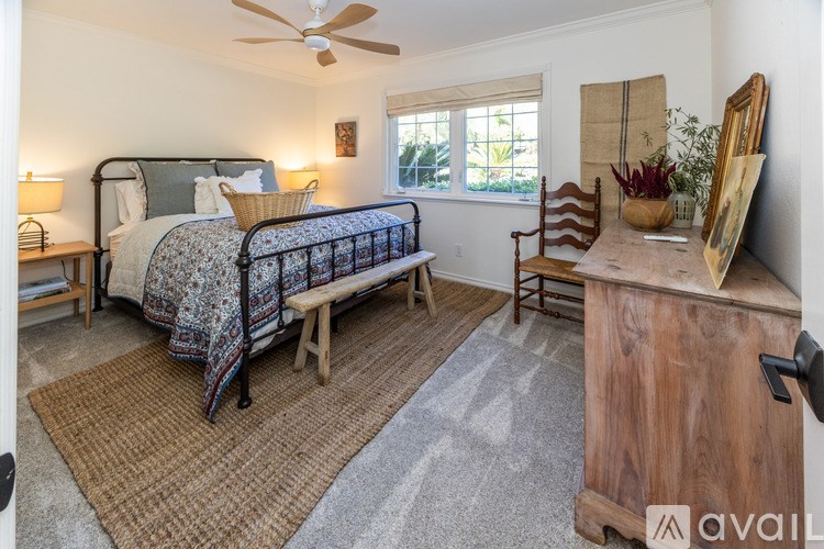 A bedroom with a bed, a chair, and a wooden cabinet.