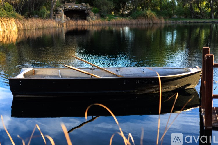 A boat is docked at a wooden pier on a calm lake.