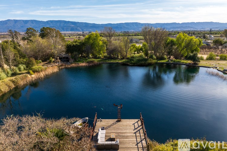 A serene lake surrounded by lush greenery and a wooden dock.
