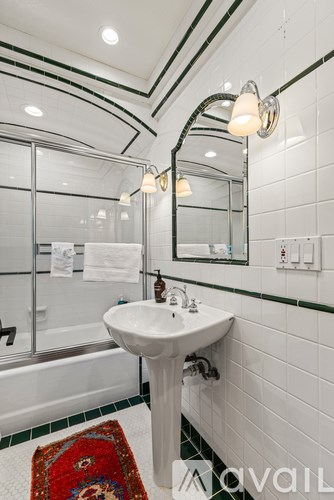 A bathroom with a sink, mirror, and a red rug.