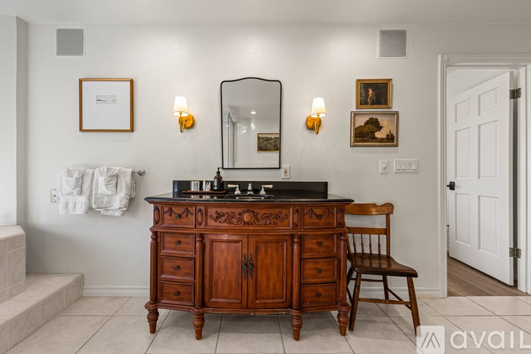 A wooden vanity with a mirror and a chair is in a room.