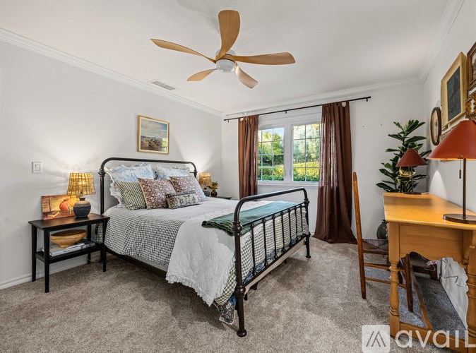 A bedroom with a bed, desk, and window.