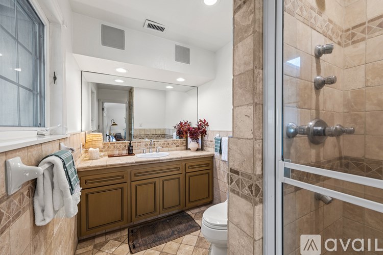 A bathroom with a brown vanity and a glass shower door.