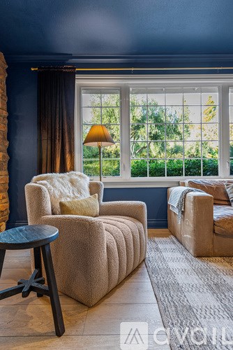 A living room with a grey couch, a brown armchair, and a small table.