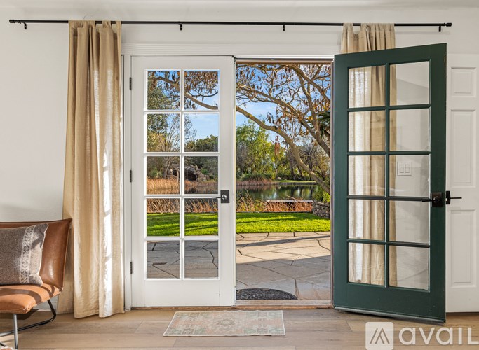 A white interior with a view of a green lawn through a glass door.