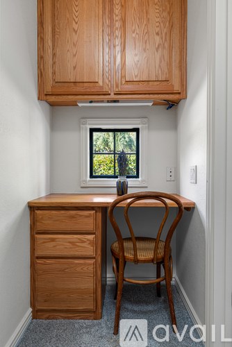 A wooden chair sits in front of a desk with a window behind it.