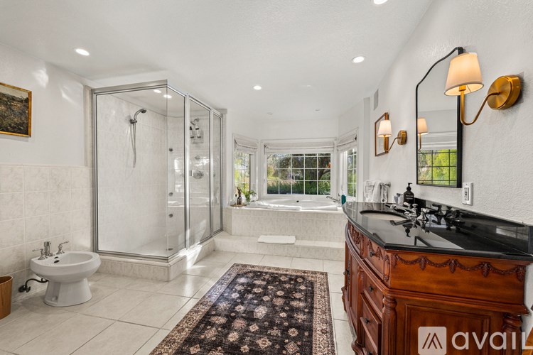 A bathroom with a glass shower stall and a white bathtub.