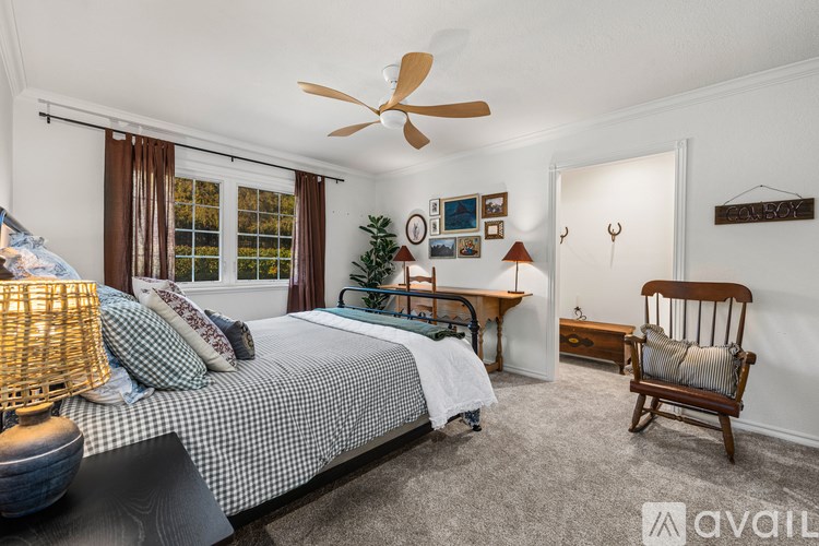 A bedroom with a bed, chair, and a fan.