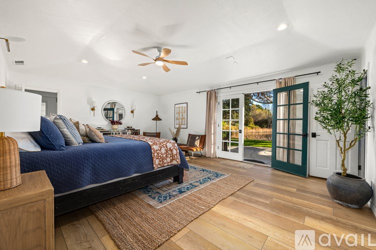A bedroom with a bed, a ceiling fan, and a rug on the floor.
