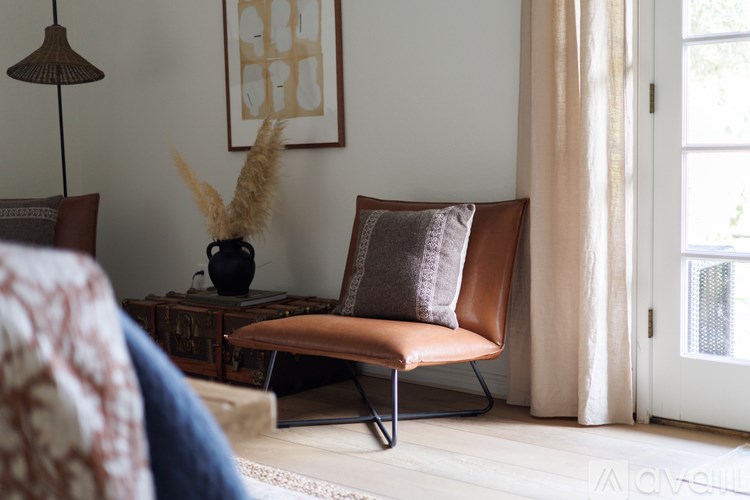A living room with a brown chair and a vase with pampas grass on a coffee table.