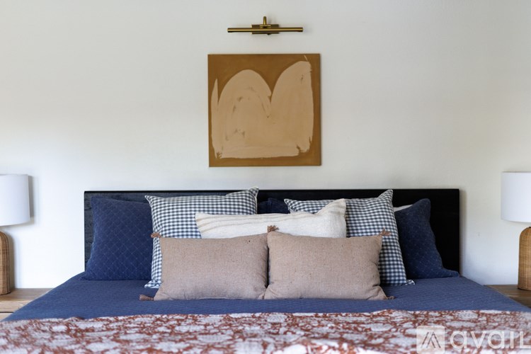 A bed with a blue headboard and a brown heart-shaped artwork on the wall.