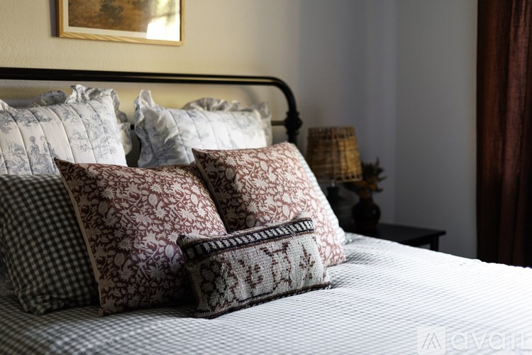 A bed with a white comforter and a pillow with a pattern of red and white flowers.