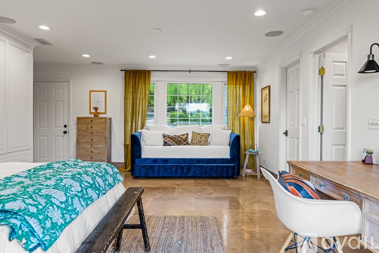 A bedroom with a bed, a couch, and a desk.